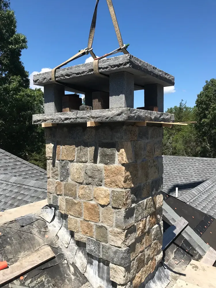 Stone chimney being set by crane