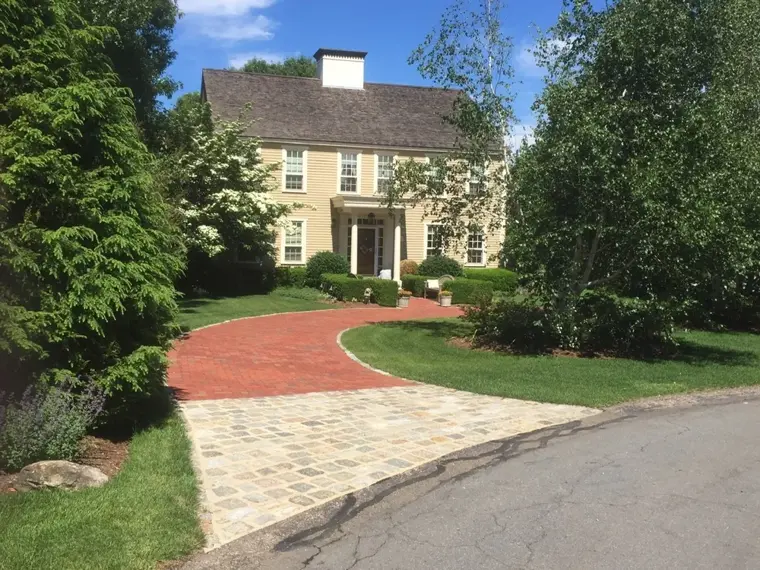 Brick walkway leading to a colonial home