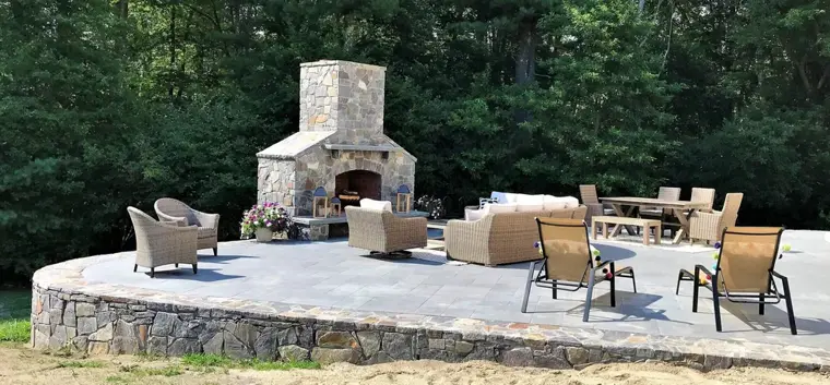 Stone patio with an outdoor fireplace and seating